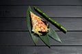 Japanese Sushi Temaki Hand Roll with salmon in Mamenori seaweed on bamboo leaves near bamboo plant stick Royalty Free Stock Photo