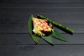 Japanese Sushi Temaki Hand Roll with salmon in Mamenori seaweed on bamboo leaves near bamboo plant stick Royalty Free Stock Photo