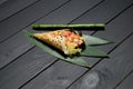 Japanese Sushi Temaki Hand Roll with salmon in Mamenori seaweed on bamboo leaves near bamboo plant stick Royalty Free Stock Photo