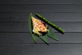 Japanese Sushi Temaki Hand Roll with salmon in Mamenori seaweed on bamboo leaves near bamboo plant stick Royalty Free Stock Photo