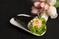 Japanese Sushi Temaki with tiger shrimp wrapped in nori seaweed served on white plate with pastel tulips on background Royalty Free Stock Photo