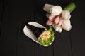 Japanese Sushi Temaki with tiger shrimp wrapped in nori seaweed served on white plate with pastel tulips on background Royalty Free Stock Photo