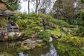 The Japanese Tea Garden with a pond surrounded by lush green trees, plants and grass and people sitting at tables having tea Royalty Free Stock Photo