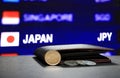 Japanese ten Yen coins on obverse JPY and pile of other Japanese coins on black floor with black wallet and digital board. Royalty Free Stock Photo