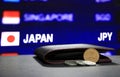 Japanese ten Yen coins on reverse JPY and pile of other Japanese coins on black floor with black wallet and digital board. Royalty Free Stock Photo