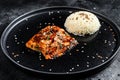 Japanese Teriyaki grilled salmon fillet glazed in delicious sauce with a side dish of rice. Black background. Top view