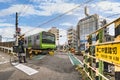 Japanese Uber Eats delivery man on bicycle waiting at a level crossing in Tokyo.