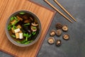 Japanese vegetarian miso soup with shiitake mushrooms, tofu cheese, seaweed and green onions in a bowl on a bamboo mat