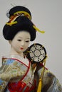 Japanese woman geisha doll in traditional richly decorated kimono costume with small Tsuzumi drum on her shoulder.