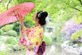Traditional Asian Japanese beautiful Geisha woman wears kimono bride with a red umbrella in a graden Royalty Free Stock Photo