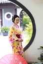 Traditional Asian Japanese beautiful Geisha woman wears kimono hold a umbrella on hand in a summer graden Royalty Free Stock Photo