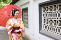 Traditional Asian Japanese beautiful Geisha bride woman wears kimono hold a umbrella in a summer nature garden Royalty Free Stock Photo