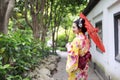 Traditional Asian Japanese beautiful bride Geisha woman wears kimono hold a white red umbrella in a summer nature garden Royalty Free Stock Photo