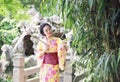 Traditional Asian Japanese beautiful woman bride wears kimono with white umbrella stand by bamboo in outdoor spring garden Royalty Free Stock Photo