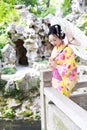 Traditional Asian Japanese beautiful woman bride wears kimono with white umbrella stand by bamboo in outdoor spring garden Royalty Free Stock Photo