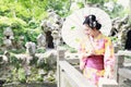 Traditional Asian Japanese beautiful woman bride wears kimono with white umbrella stand by bamboo in outdoor spring garden Royalty Free Stock Photo