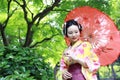 Traditional Asian Japanese woman in a garden hold a red umbrella