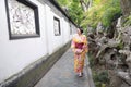 Traditional Asian Japanese beautiful woman wears kimono in a spring garden park stand by bamboo enjoy free time fan Royalty Free Stock Photo