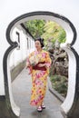 Traditional Asian Japanese beautiful woman wears kimono in a spring garden park stand by bamboo enjoy free time fan Royalty Free Stock Photo