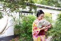 Traditional Asian Japanese beautiful Geisha woman wears kimono hold a fan on hand in a summer nature