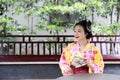 Traditional Asian Japanese beautiful Geisha woman bride wears kimono hold a fan reading book in a summer nature Royalty Free Stock Photo