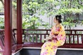 Traditional Asian Japanese beautiful Geisha woman bride wears kimono hold a fan sit on a pavilion in a summer nature Royalty Free Stock Photo