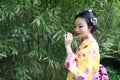 Traditional Asian Japanese woman with kimono Japanese bride smiling stand by bamboo in a spring park Royalty Free Stock Photo