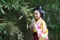 Traditional Asian Japanese beautiful Geisha woman bride wears kimono hold a fan in a summer nature Royalty Free Stock Photo