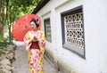 Traditional Asian Japanese beautiful bride Geisha woman wears kimono hold a white red umbrella in a summer nature garden Royalty Free Stock Photo