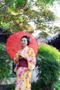 Traditional Asian Japanese woman in a garden hold a red umbrella Royalty Free Stock Photo