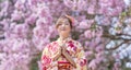 Japanese woman in traditional kimono dress is making a new year wish for good fortune while walking in the park at cherry blossom Royalty Free Stock Photo