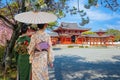 Japanese woman in a traditional Kimono dress at the Phoenix Hall of Byodo-in Temple in Kyoto during full bloom cherry blossom Royalty Free Stock Photo