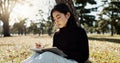 Japanese woman, writing and book in park, thinking and relax by tree, grass or sunshine for peace. Girl, person or Royalty Free Stock Photo