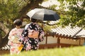 Japanese women with black umbrella dressed with traditional kimono in a green garden, Nara, Japan