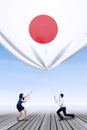 Japanese workers bring down a japanese flag Royalty Free Stock Photo