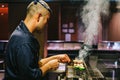 Japanese Yakitori Chef is grilling chicken marinated with ginger, garlic and soy sauce and cucumber with a lot of smoke