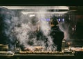 Japanese Yakitori Chef is grilling chicken marinated with ginger, garlic and soy sauce with a lot of smoke