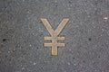 The Japanese yen sign made of yellow metal is placed on the asphalt. Japanese money, finance infographic design element