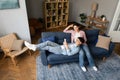 Japanese Young Couple Using Smartphone Resting On Sofa At Home