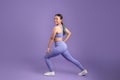 Japanese young woman stretching legs doing lunges on purple studio background Royalty Free Stock Photo