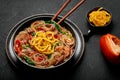 Japchae in black bowl on dark slate table top. Korean cuisine glass chapchae noodles dish with vegetables and meat Royalty Free Stock Photo