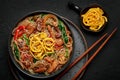 Japchae in black bowl on dark slate table top. Korean cuisine glass chapchae noodles dish with vegetables and meat Royalty Free Stock Photo