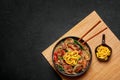 Japchae in black bowl on dark slate table top. Korean cuisine glass chapchae noodles dish with vegetables and meat