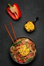 Japchae in black bowl on dark slate table top. Korean cuisine glass chapchae noodles dish with vegetables and meat