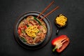Japchae in black bowl on dark slate table top. Korean cuisine glass chapchae noodles dish with vegetables and meat Royalty Free Stock Photo