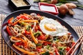 Japchae korean dish in a black plate, close up