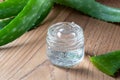 Aloe vera gel in a glass jar, with fresh aloe vera plant in the background