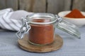 Jar with aromatic paprika powder on grey wooden table Royalty Free Stock Photo