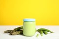 Jar with baby food, fresh pea pods and asparagus on white wooden table against background Royalty Free Stock Photo