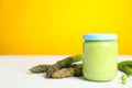 Jar with baby food, fresh pea pods and asparagus on white wooden table against background, space for text Royalty Free Stock Photo